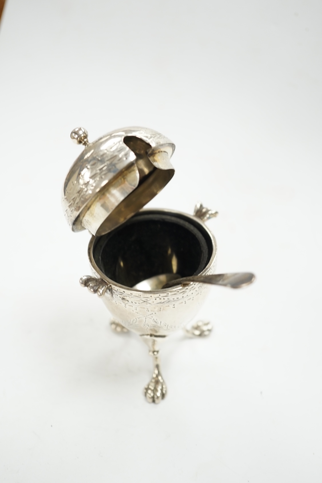 A Victorian silver egg shaped mustard pot, on paw feet, London, 1867, 10.5cm, with an earlier silver mustard ladle. Condition - fair